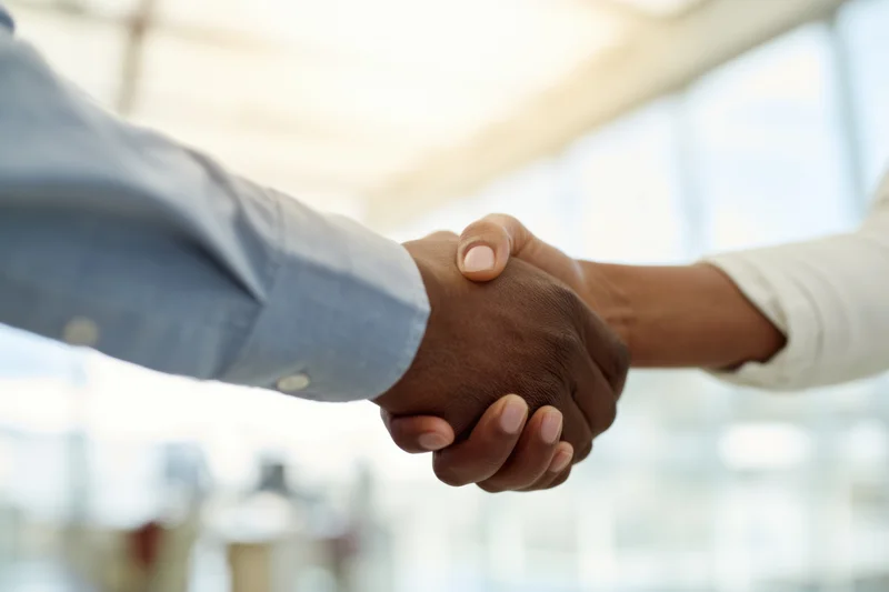 Two professionals shaking hands in a bright modern office
