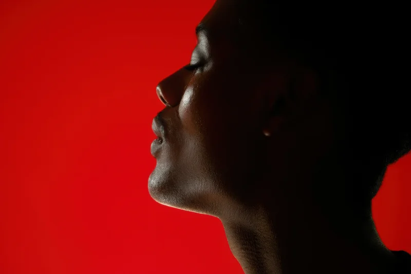 Silhouette of a woman in profile against a bold red background