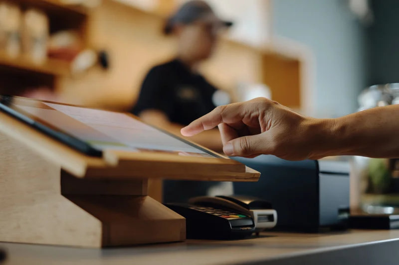 Hand tapping tablet point-of-sale screen at retail counter