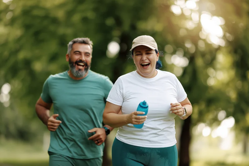 Couple jogging together in a park laughing mid-run