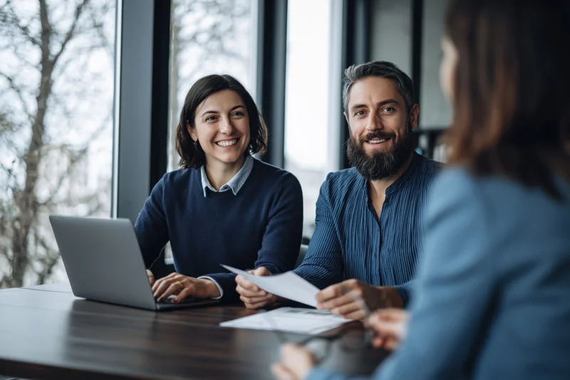 Young couple smiling during consultation with advisor at office desk