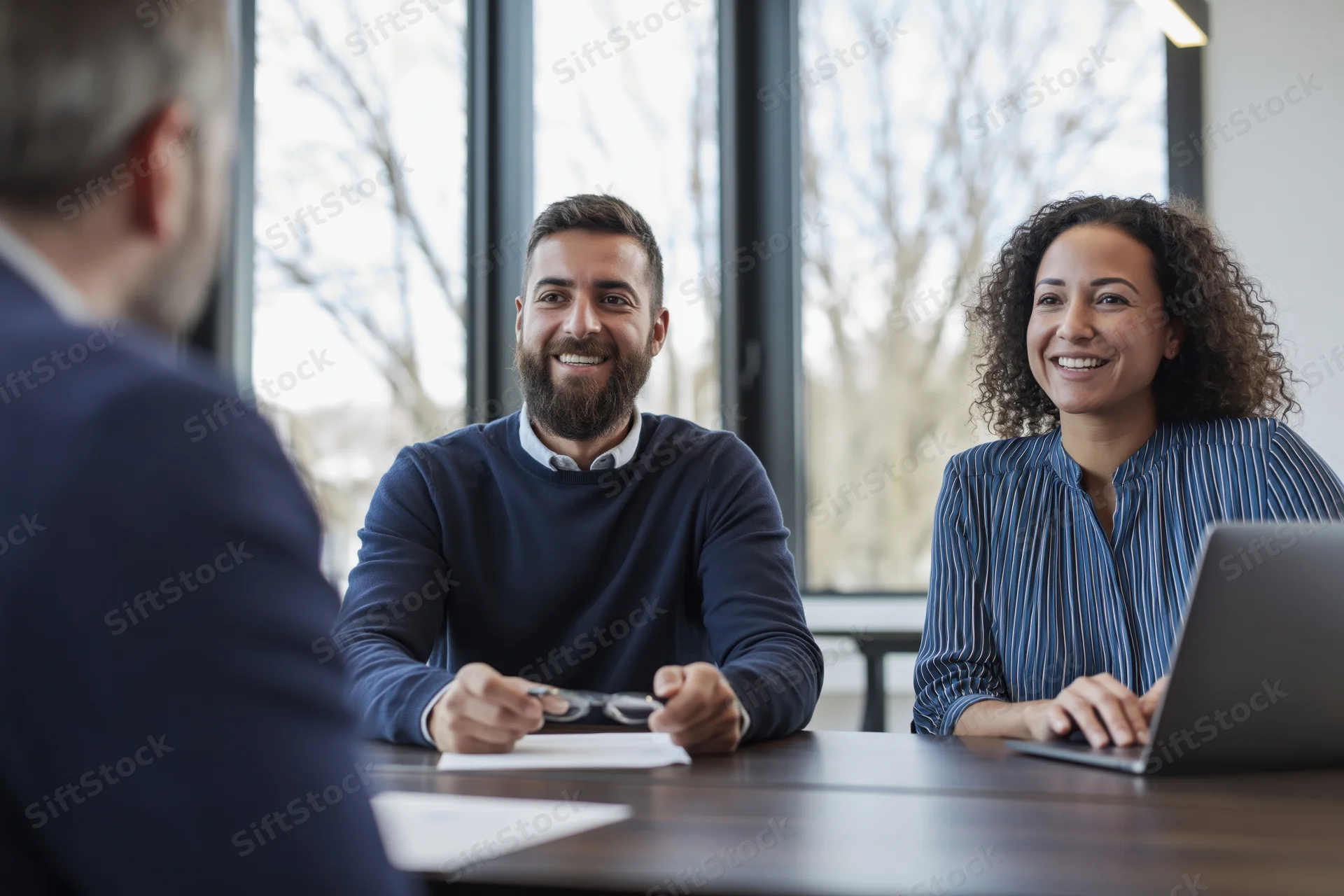 Young couple smiling during business meeting with consultant at office desk