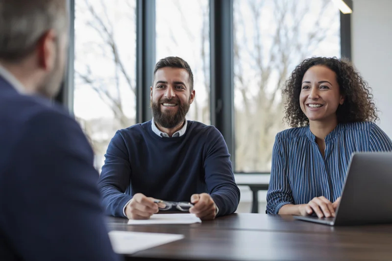 Young couple smiling during business meeting with consultant at office desk