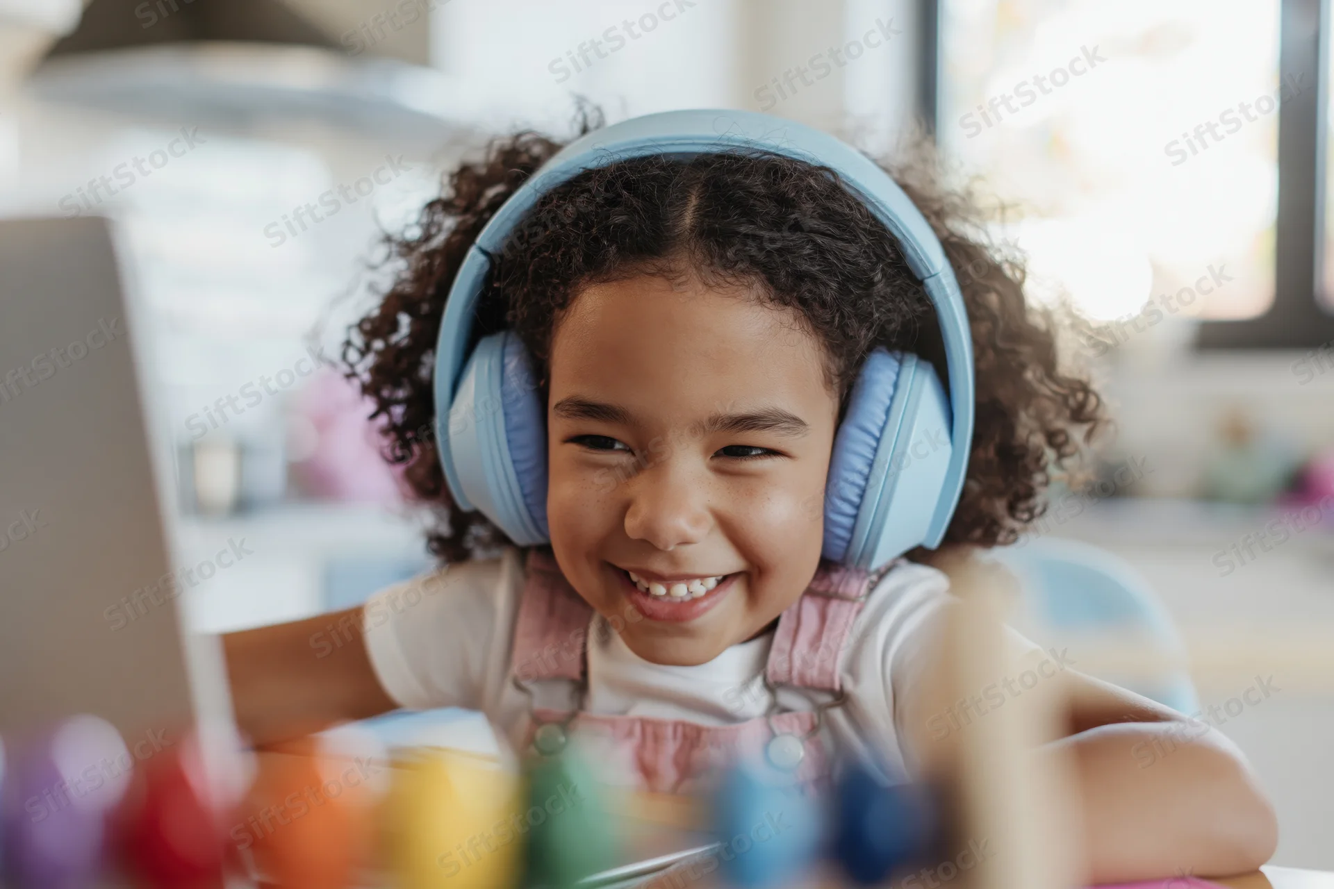 Young girl smiling while using laptop with headphones at home