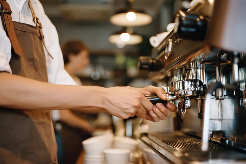 Barista operating espresso machine in a cafe