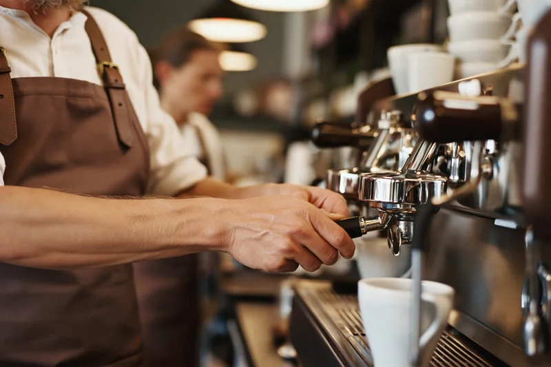 Barista operating espresso machine in cafe