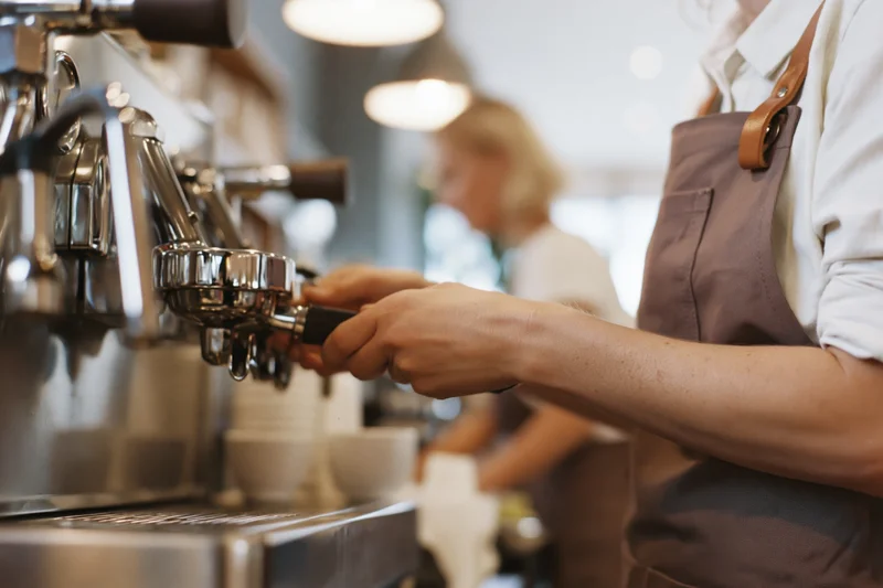 Barista operating espresso machine in a cafe