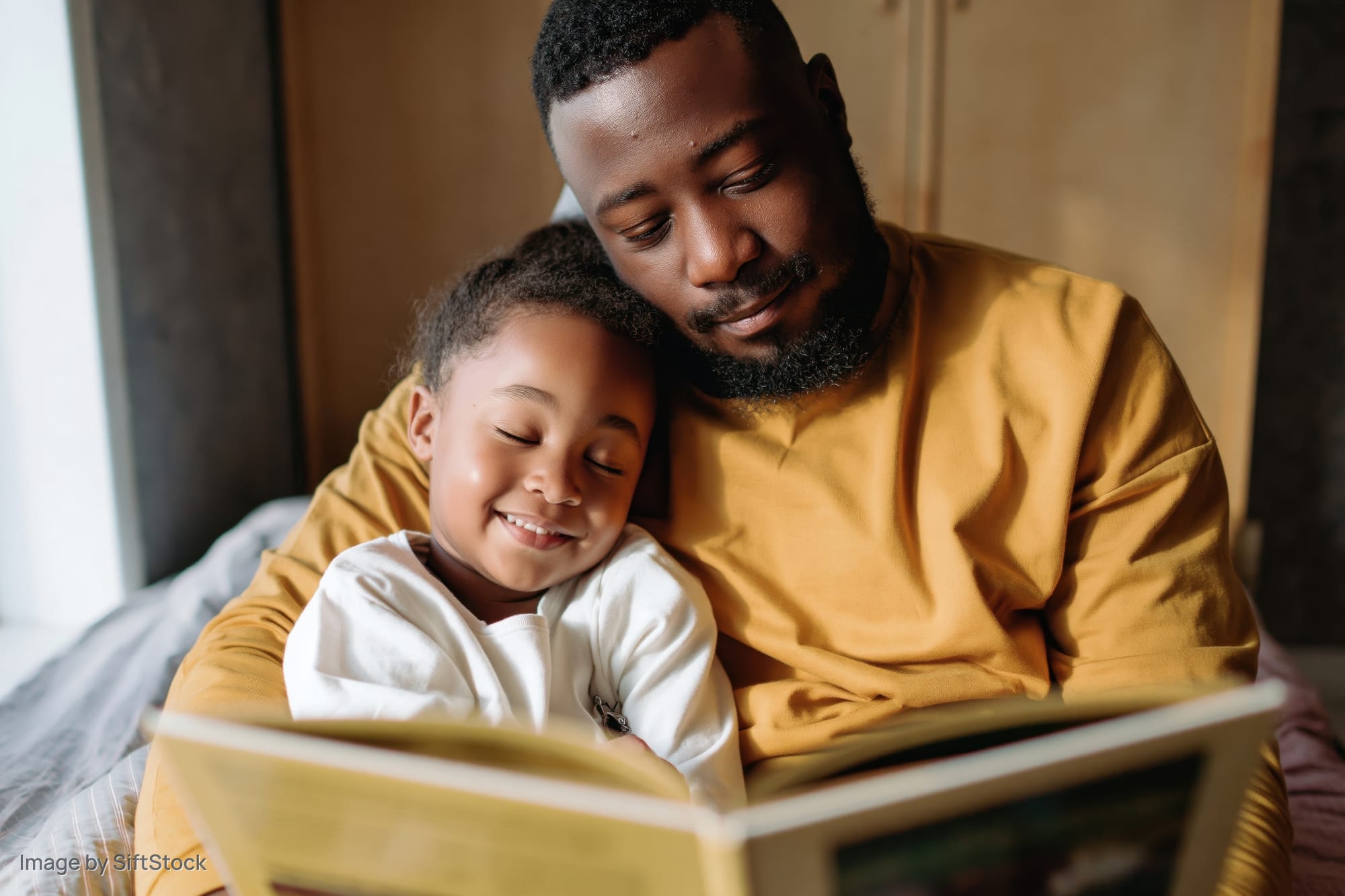 Black father reading a picture book to his young daughter