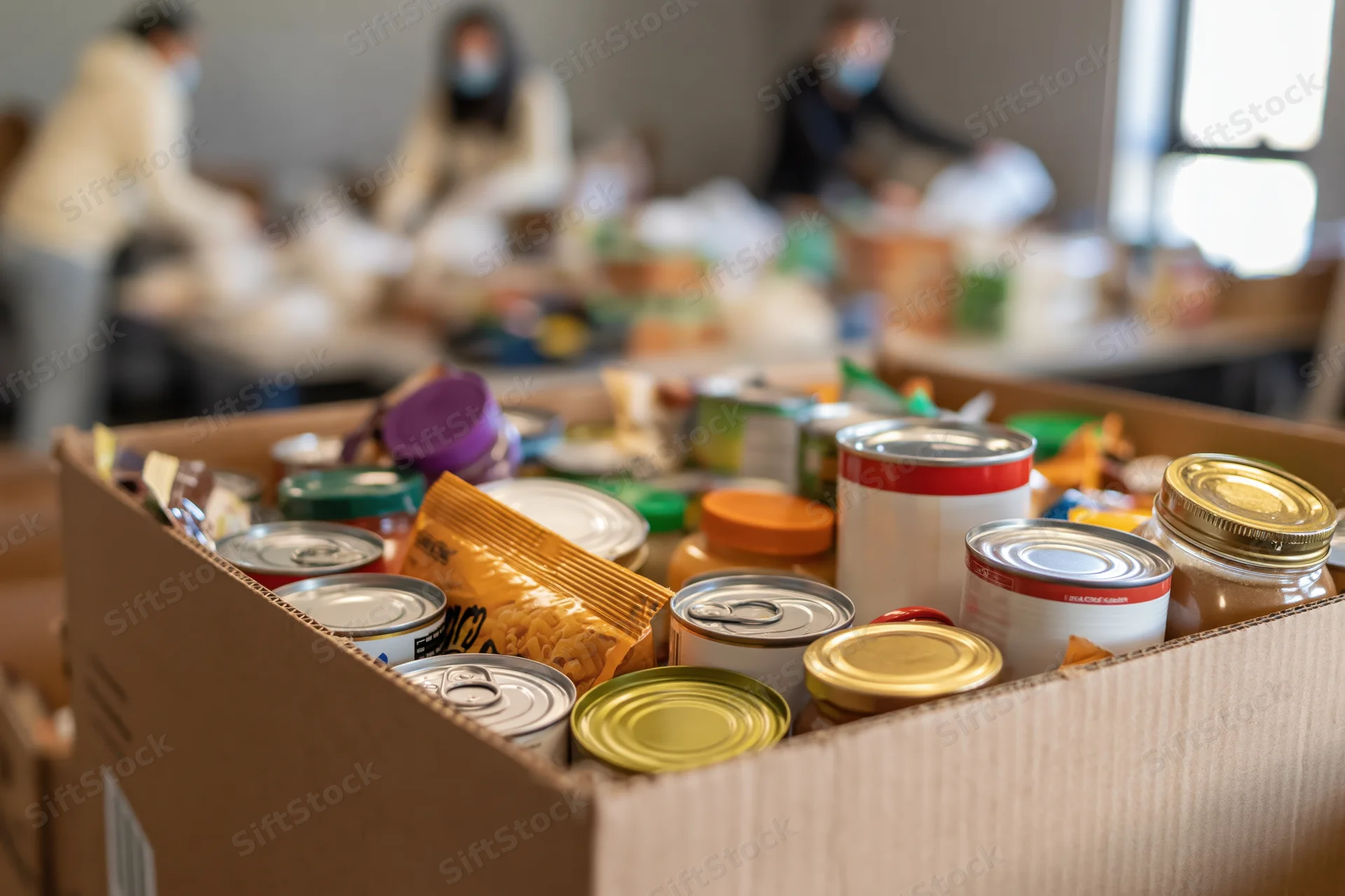 Cardboard donation box filled with canned goods and packaged food in a community aid setting