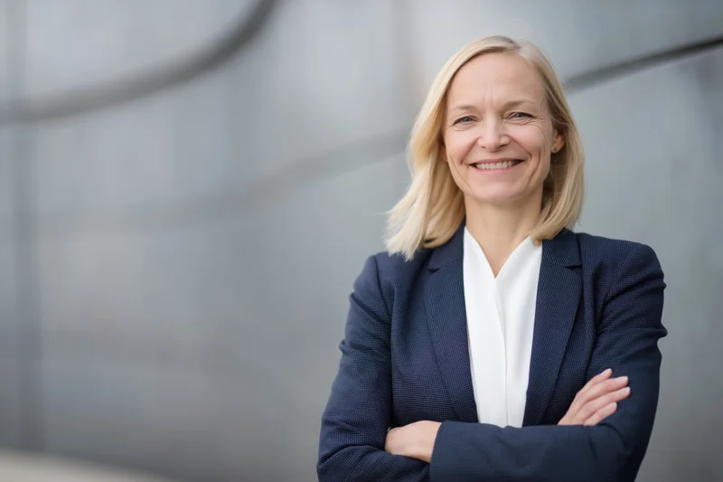 Confident middle-aged businesswoman standing with arms crossed in front of modern office building