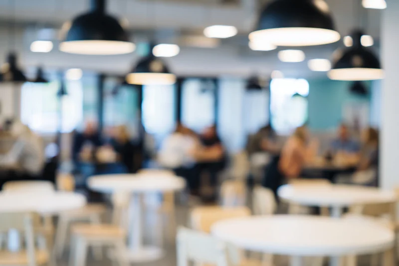 Blurred interior of a modern cafe with tables and chairs under pendant lights