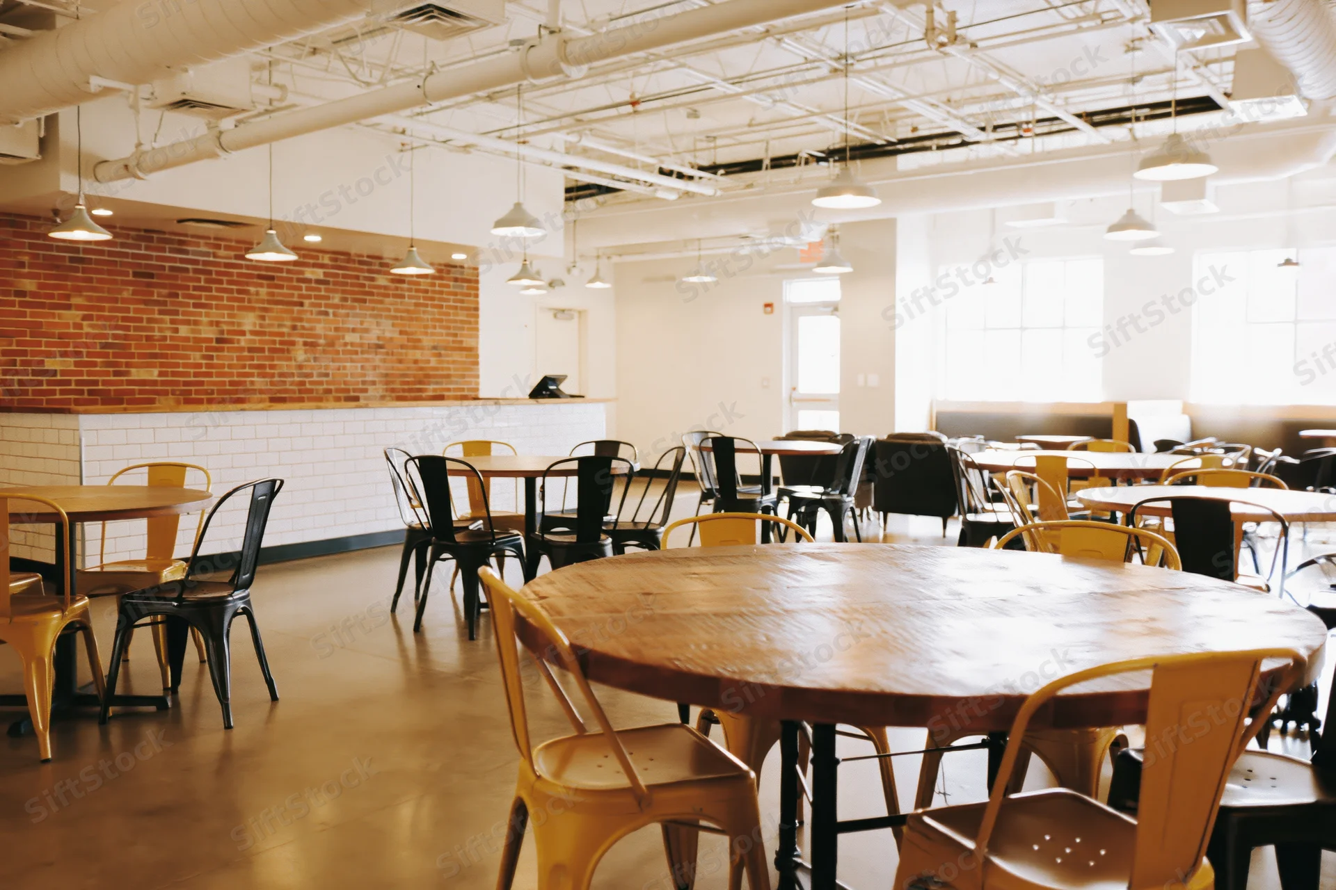 Empty industrial-style cafe interior with round wooden tables and metal chairs arranged in open space
