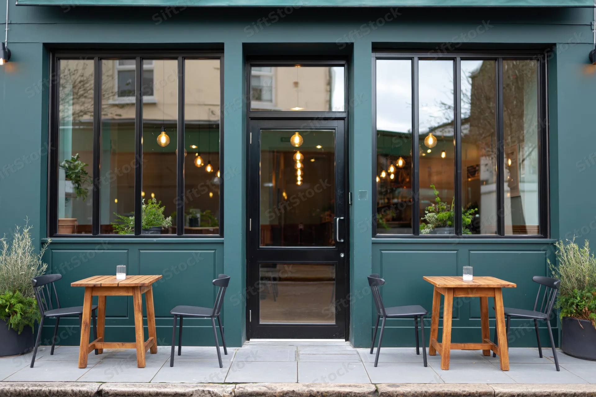 Modern cafe exterior with outdoor seating and teal facade on sidewalk