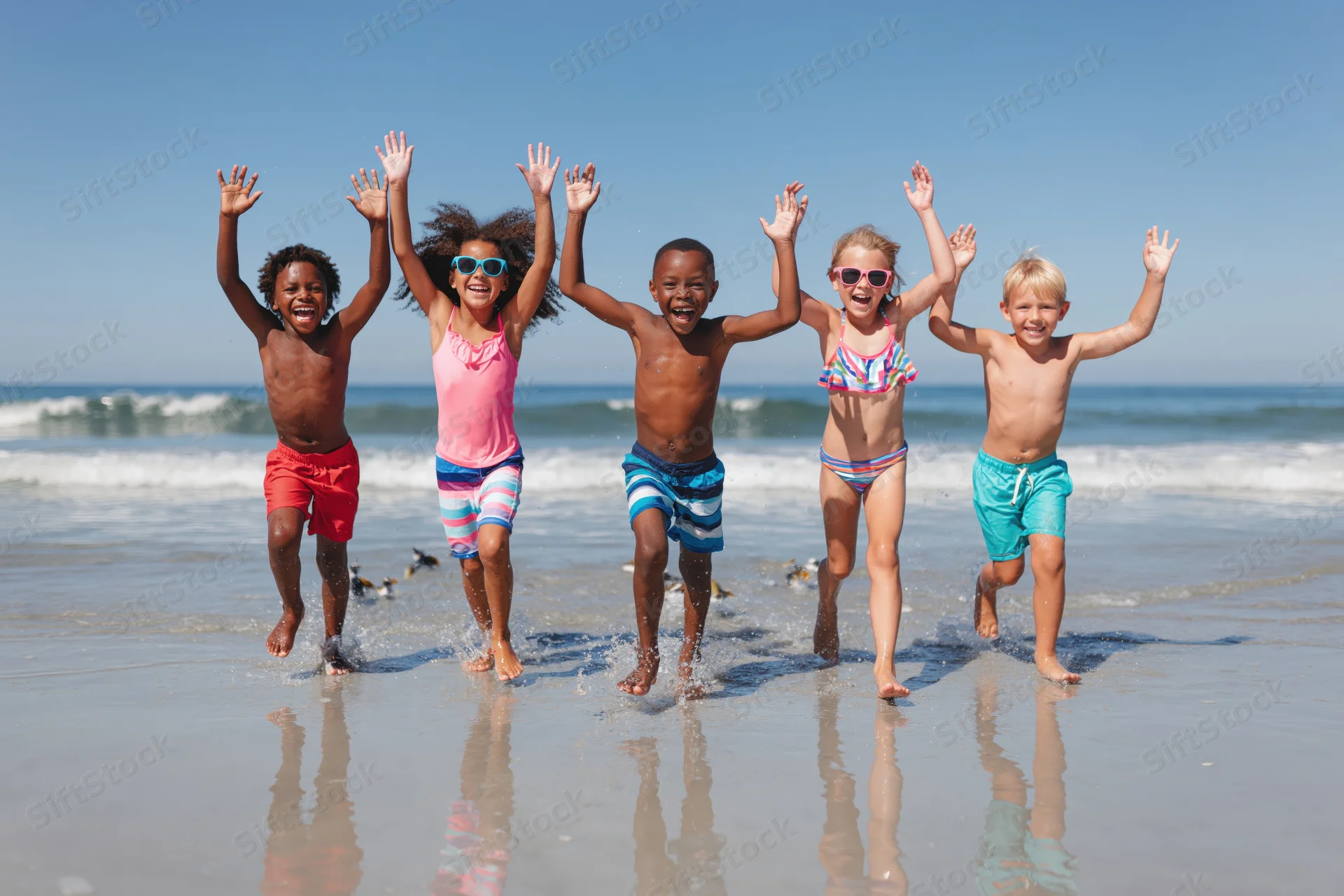Five diverse children running joyfully along the wet sand at the beach