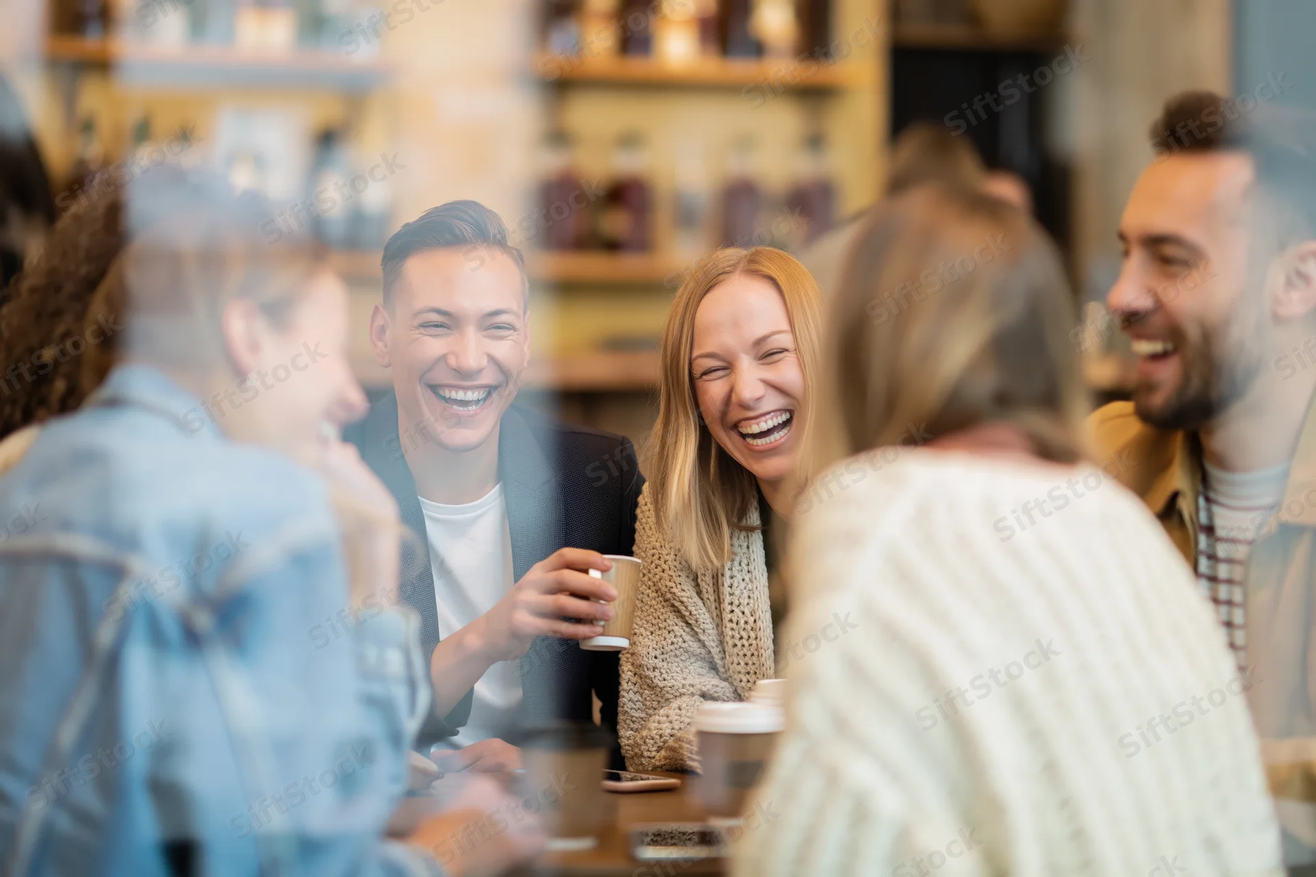 Friends laughing together around a small cafe table
