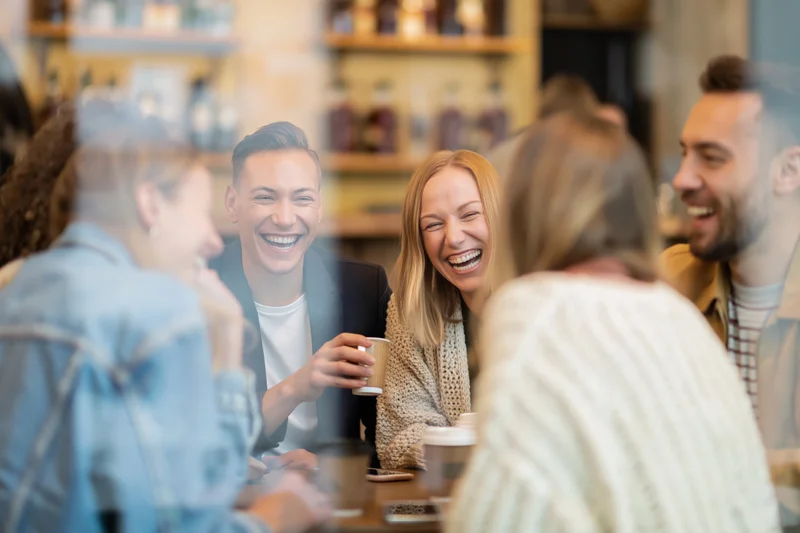 Friends laughing together around a small cafe table