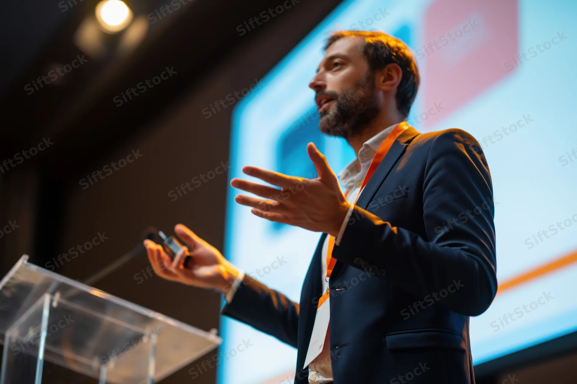 Man speaking at podium gesturing during presentation at conference