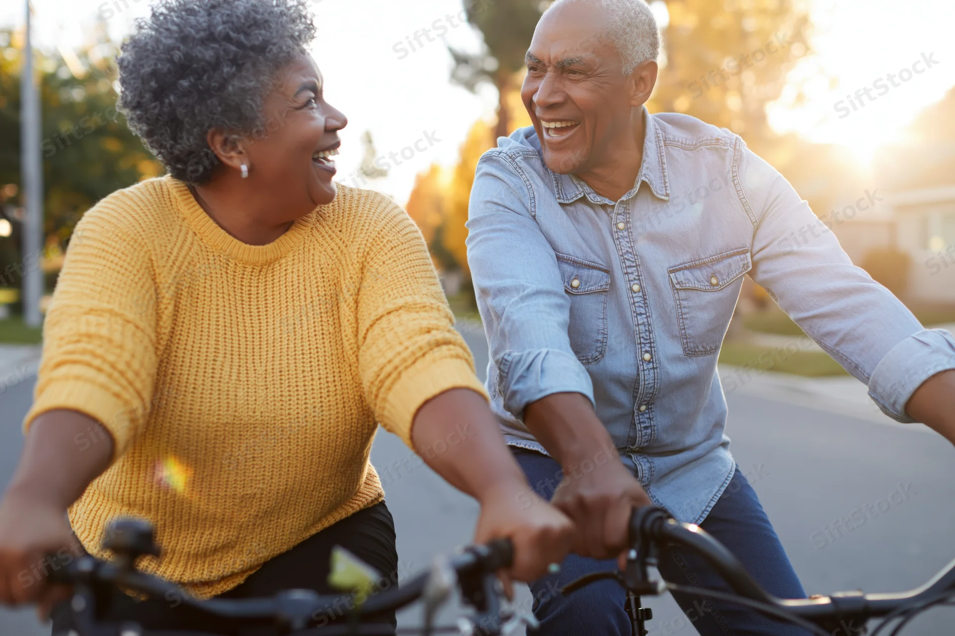 Senior black couple riding bicycles together on a suburban street at golden hour