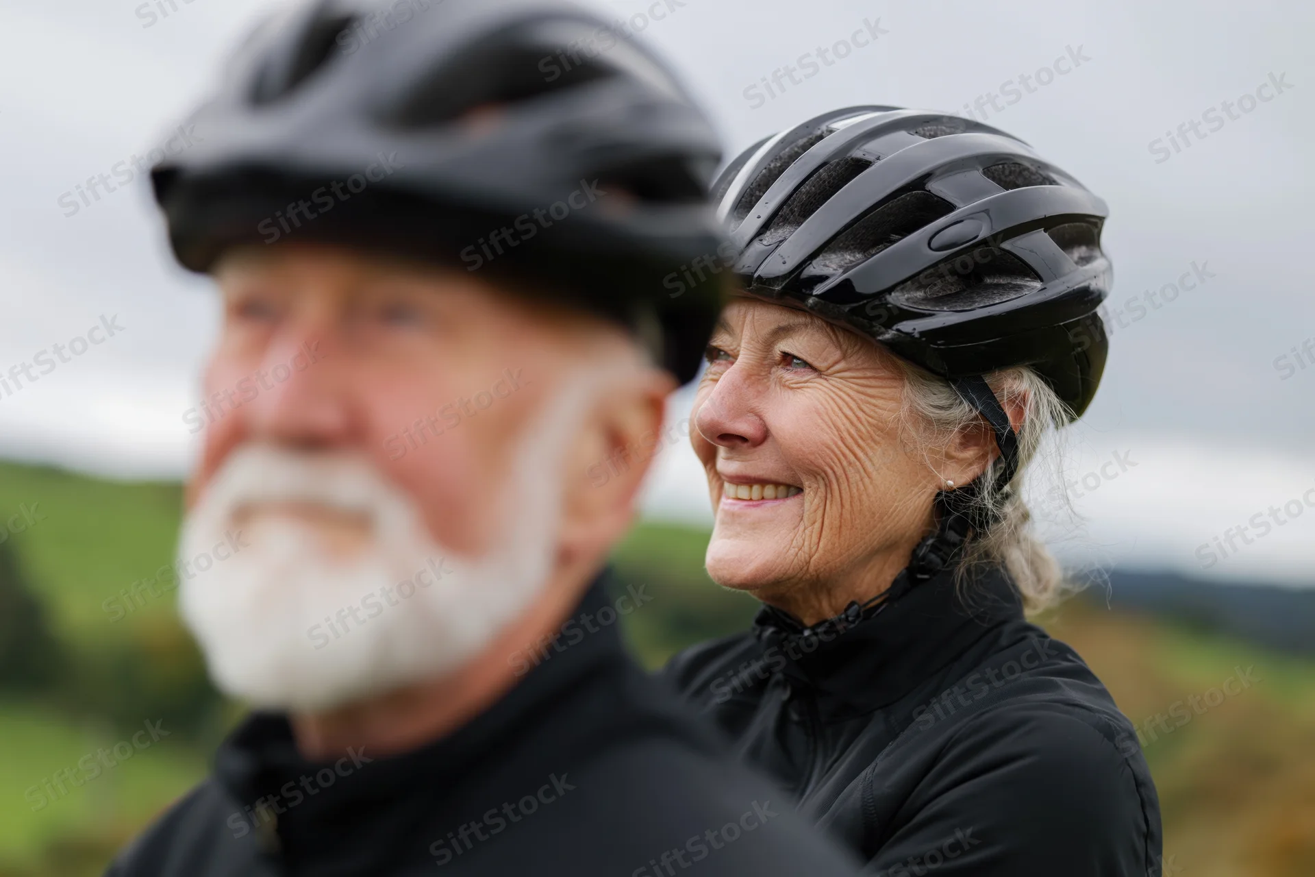 Senior couple wearing bicycle helmets outdoors in a green countryside landscape