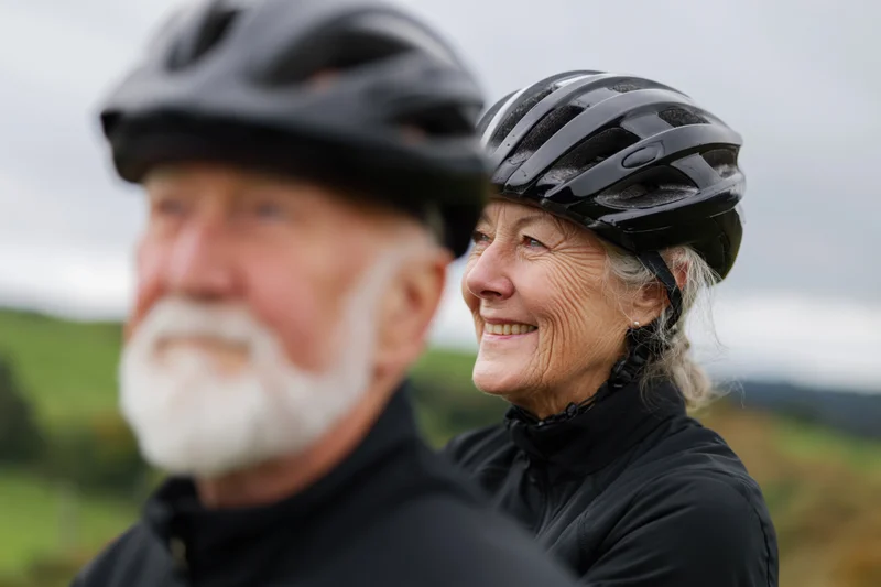 Senior couple wearing bicycle helmets outdoors in a green countryside landscape
