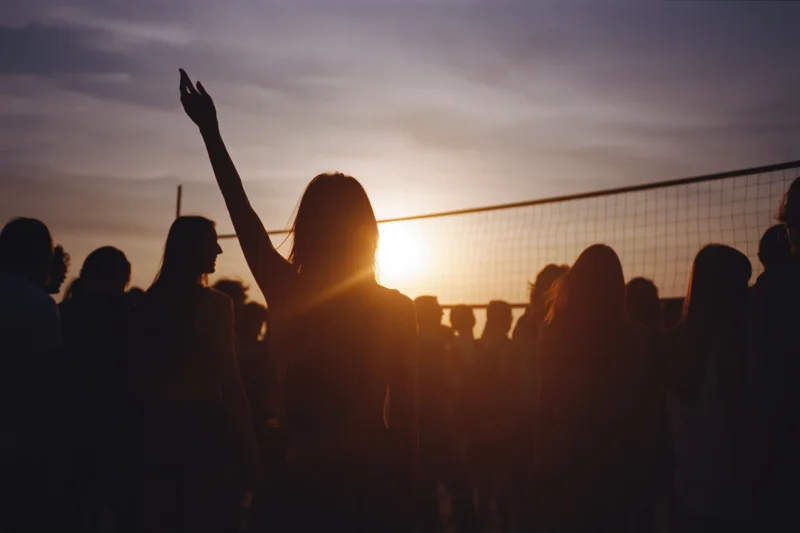 Silhouettes of young people gathered on a beach at sunset