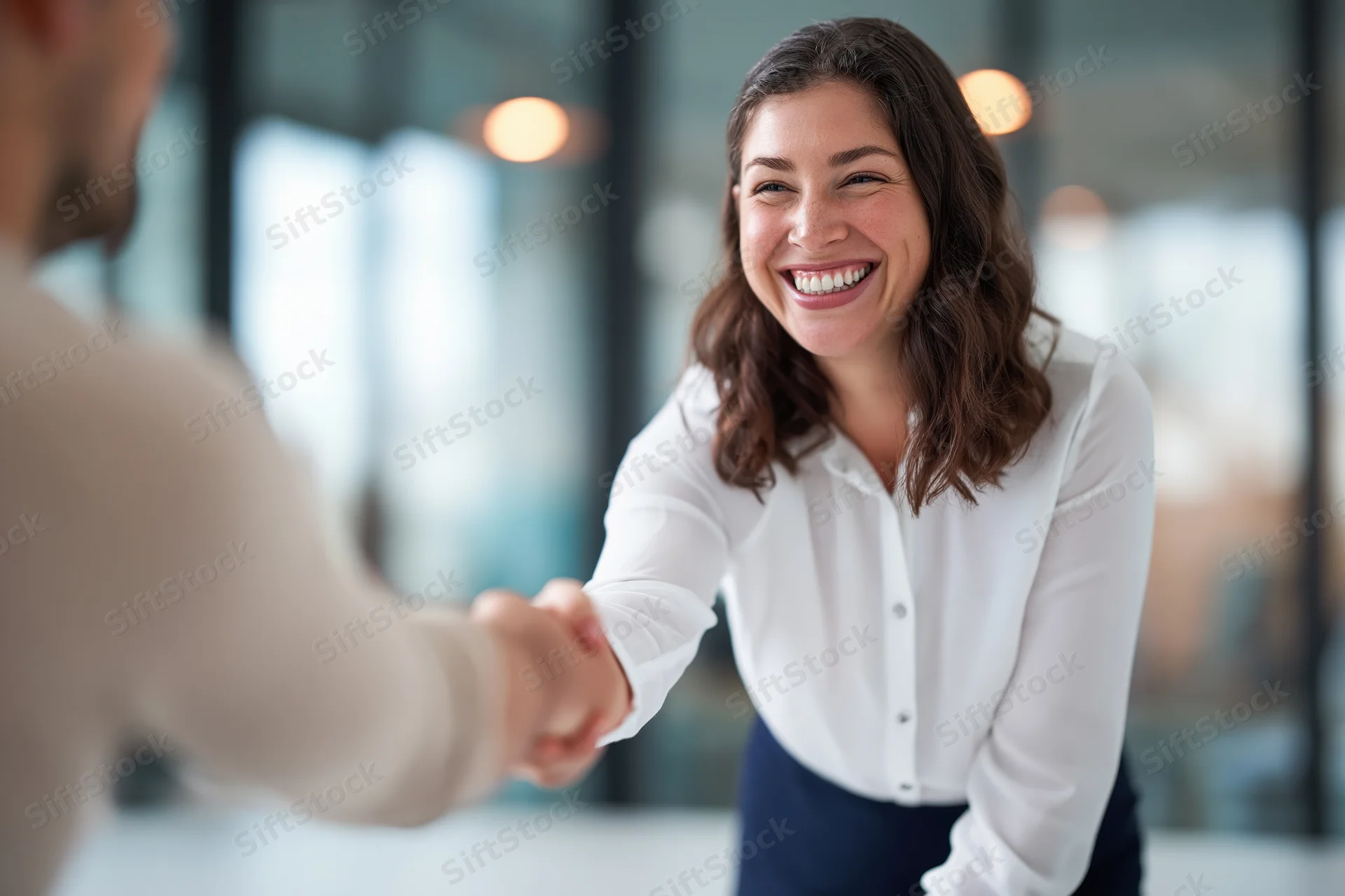 Smiling businesswoman shaking hands with a man in an office setting