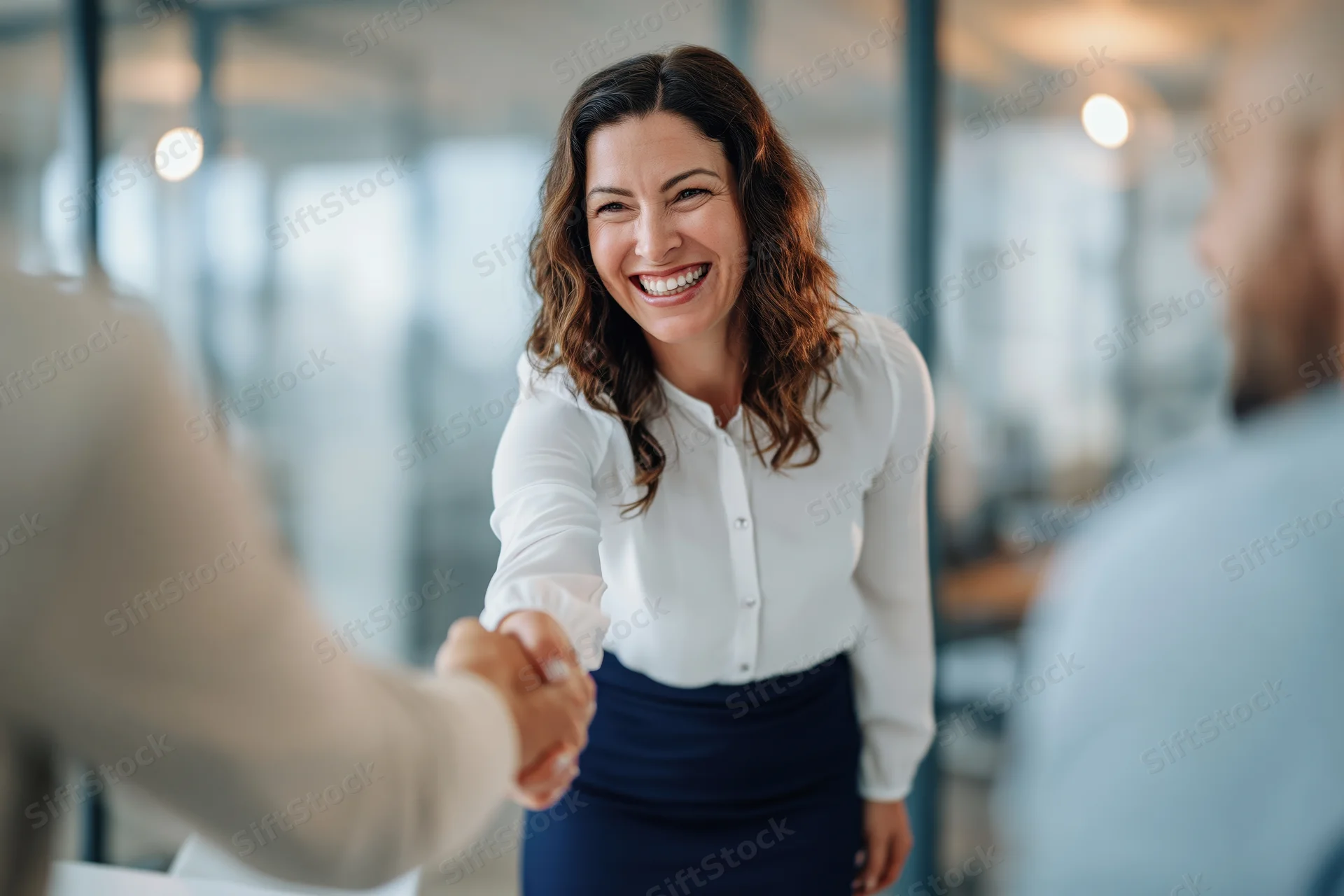 Smiling businesswoman shaking hands in modern office setting