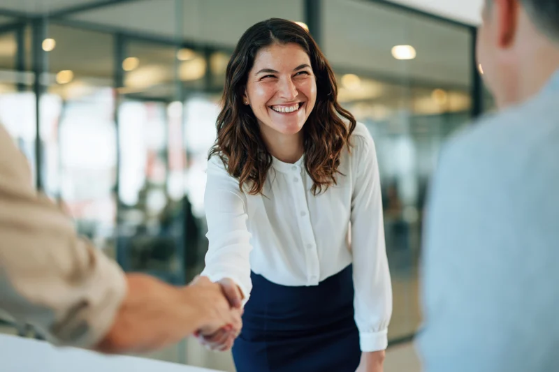 Smiling businesswoman shaking hands in modern office setting