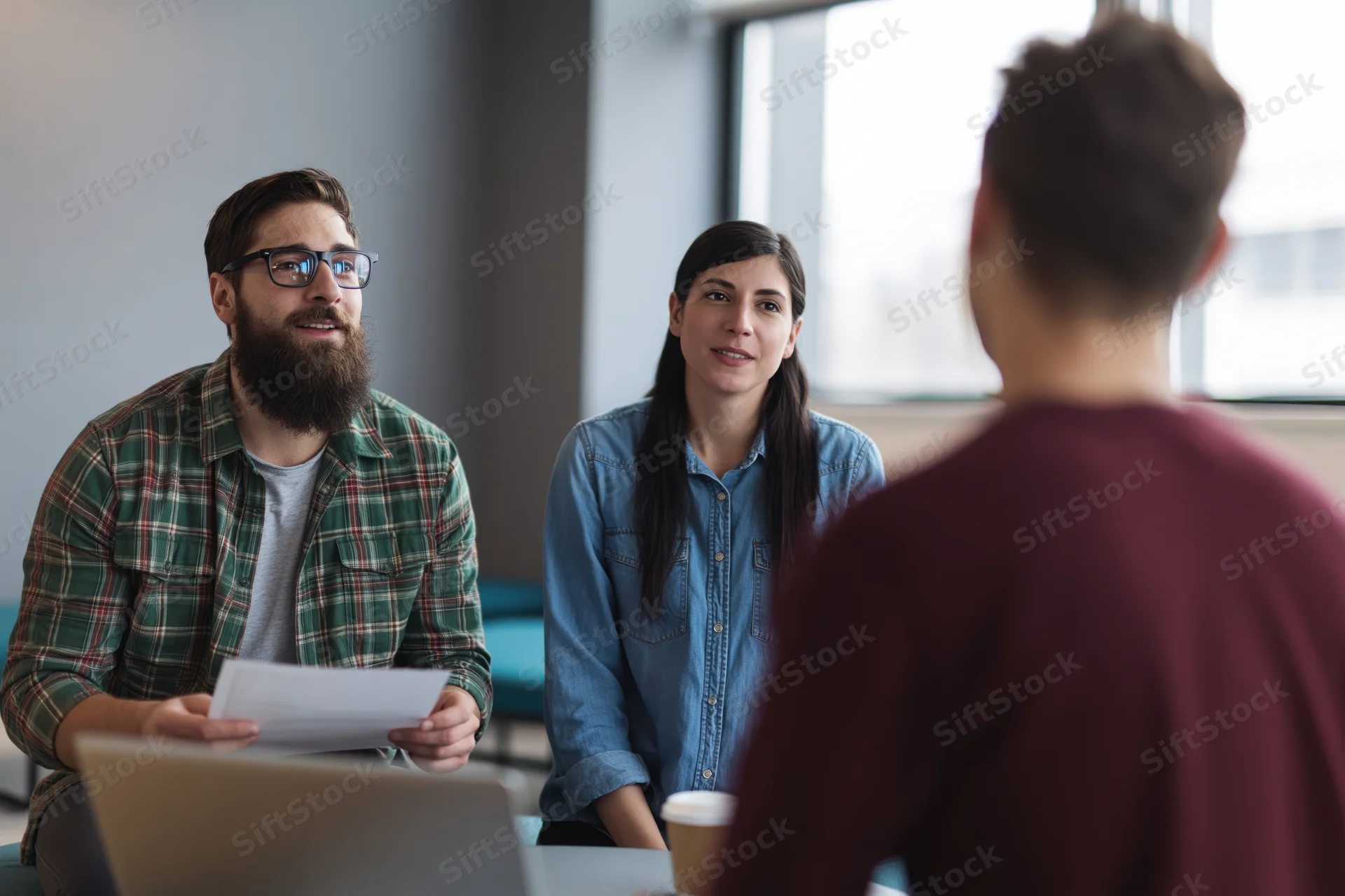 Three colleagues discussing a project in a casual office lounge