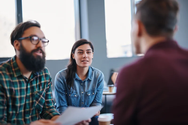 Three colleagues discussing a project in a casual office lounge