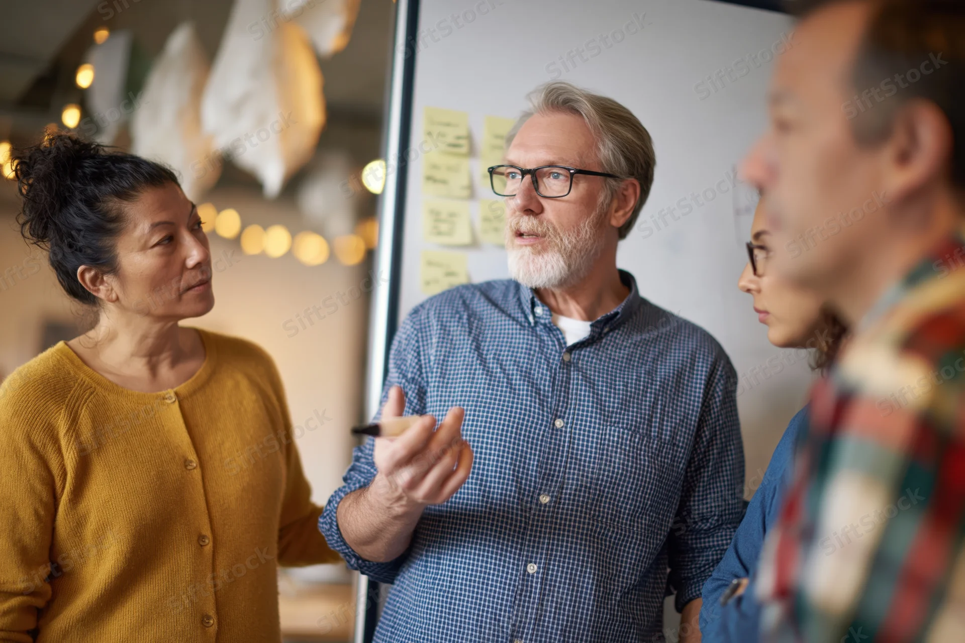Three coworkers discussing ideas around a whiteboard in an office meeting space