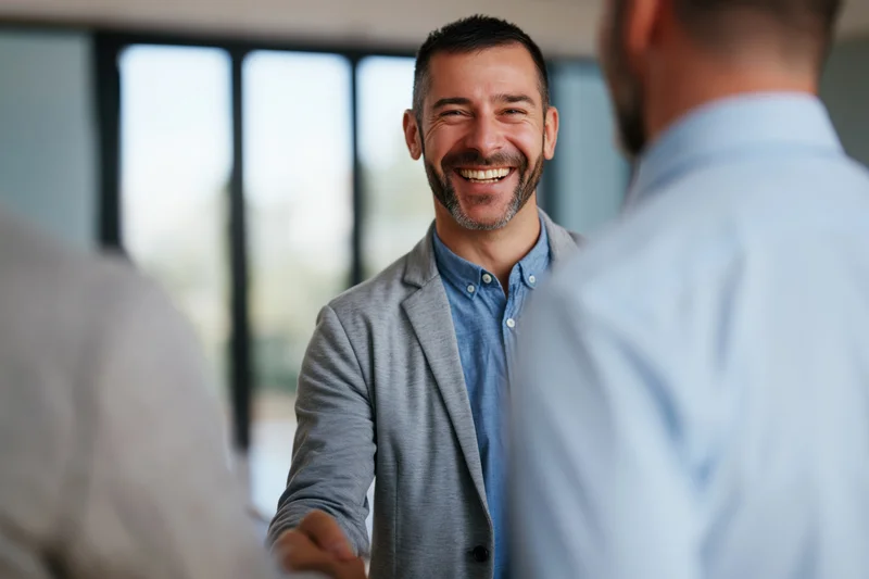 Businessman smiling during handshake in modern office with colleagues