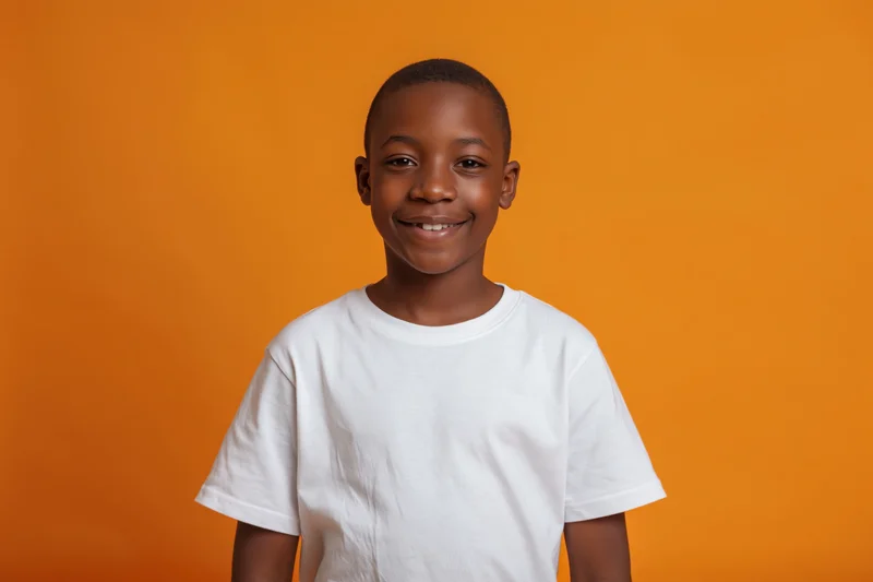 Young black boy smiling in white tshirt against orange background