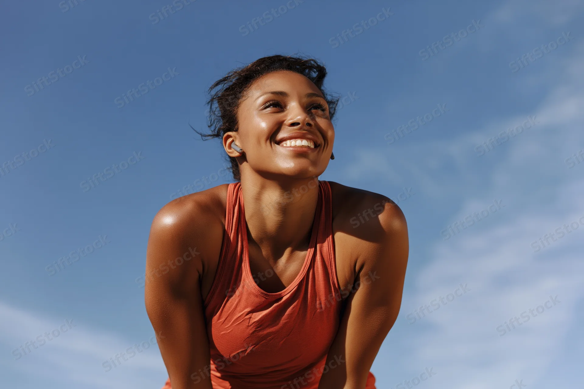 Young black woman smiling during workout pause outdoors under blue sky