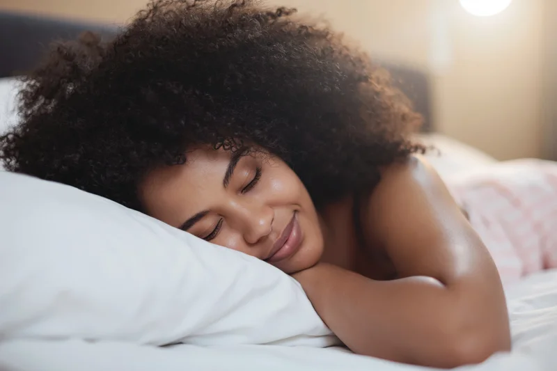 Young black woman sleeping peacefully on a pillow in a cozy bedroom