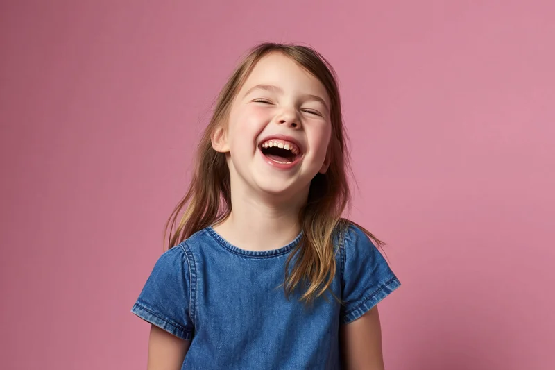 Young girl laughing with wide open mouth against pink background