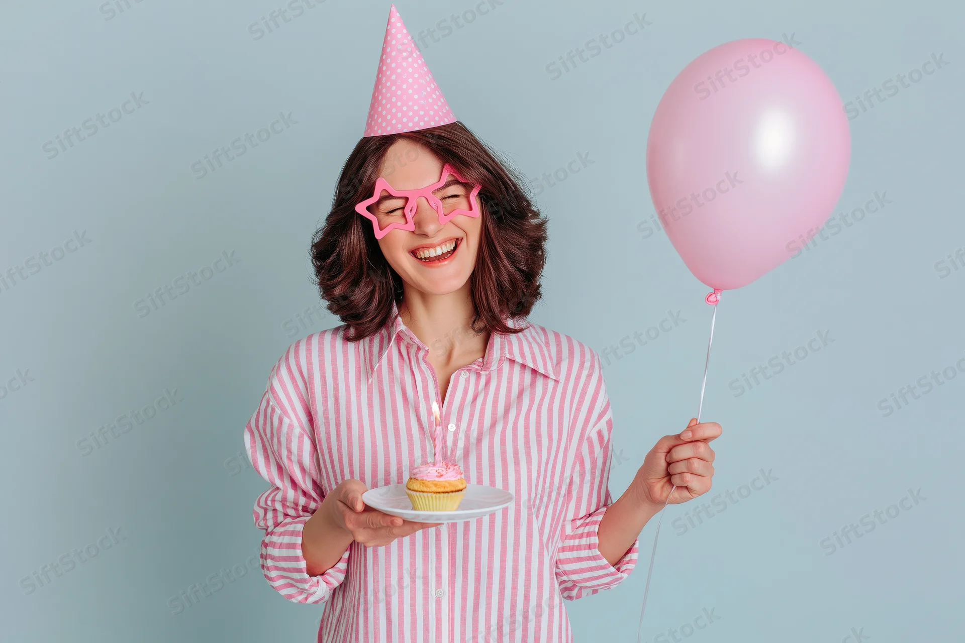 Woman smiling with eyes closed holding a cupcake and balloon at a birthday party