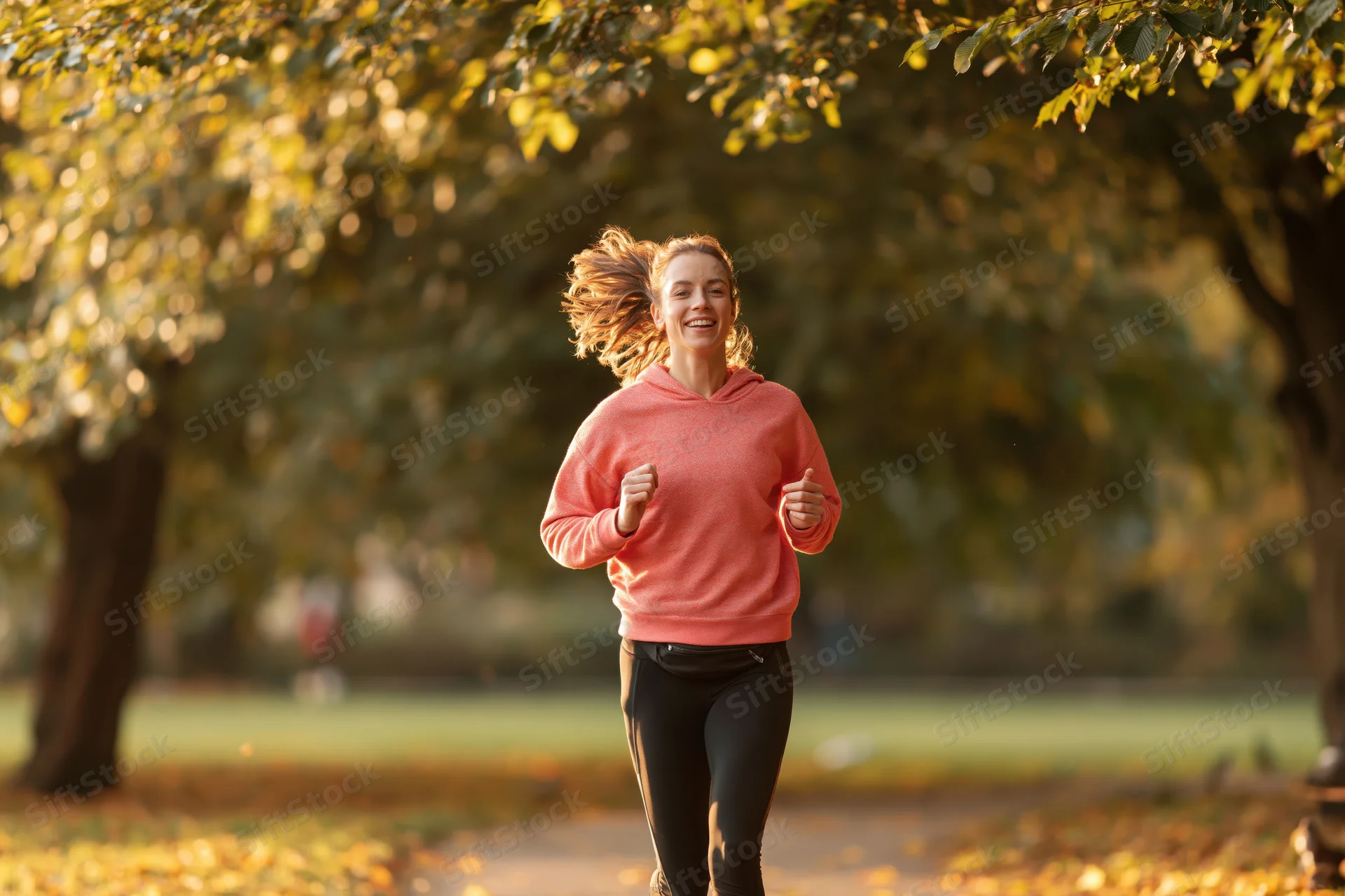 Woman jogging on a park path in autumn smiling mid-stride