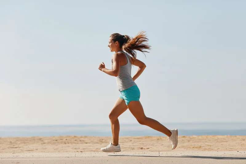 Woman running in profile along a coastal path by the beach