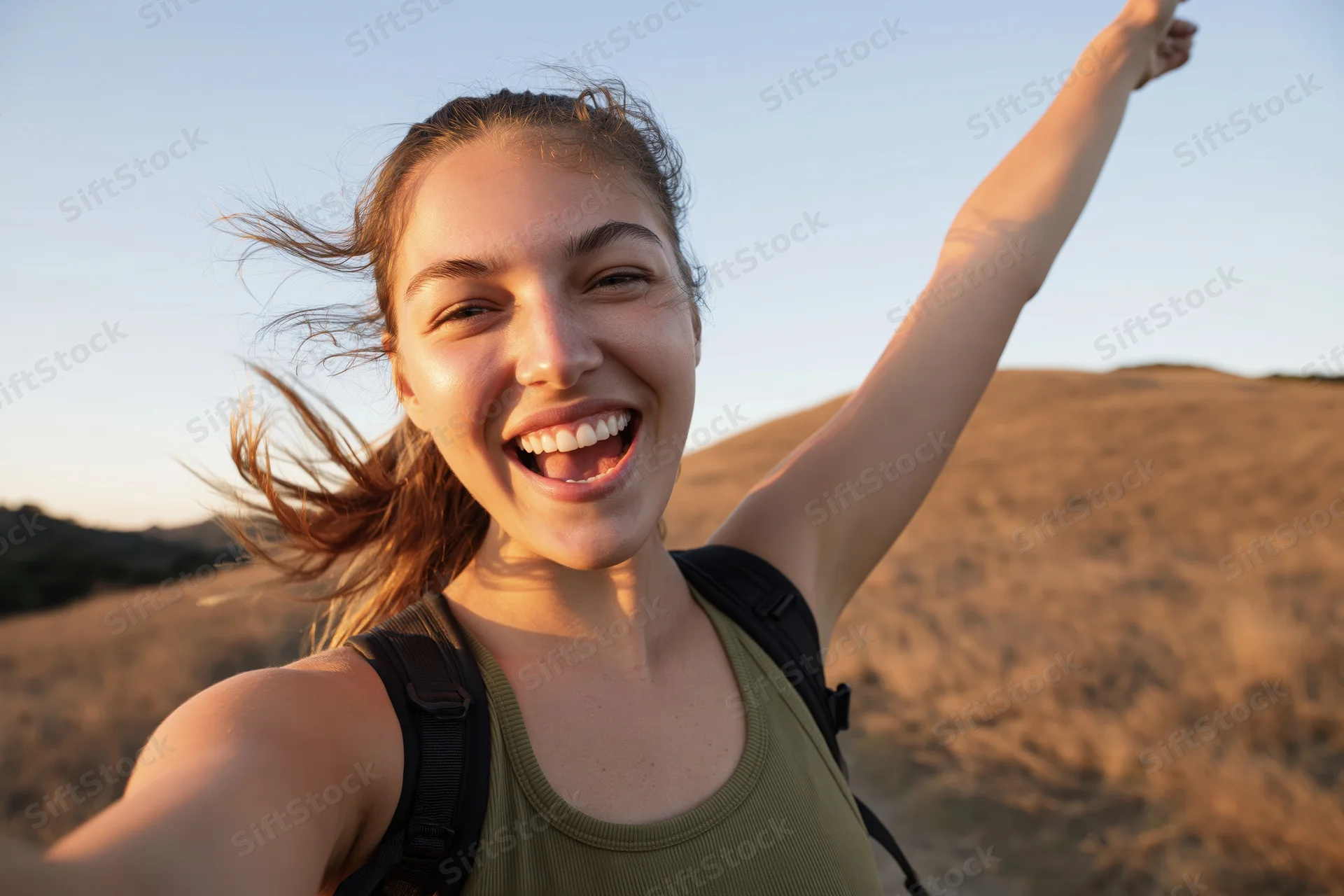 Woman taking a selfie while hiking on a sandy dune at sunset