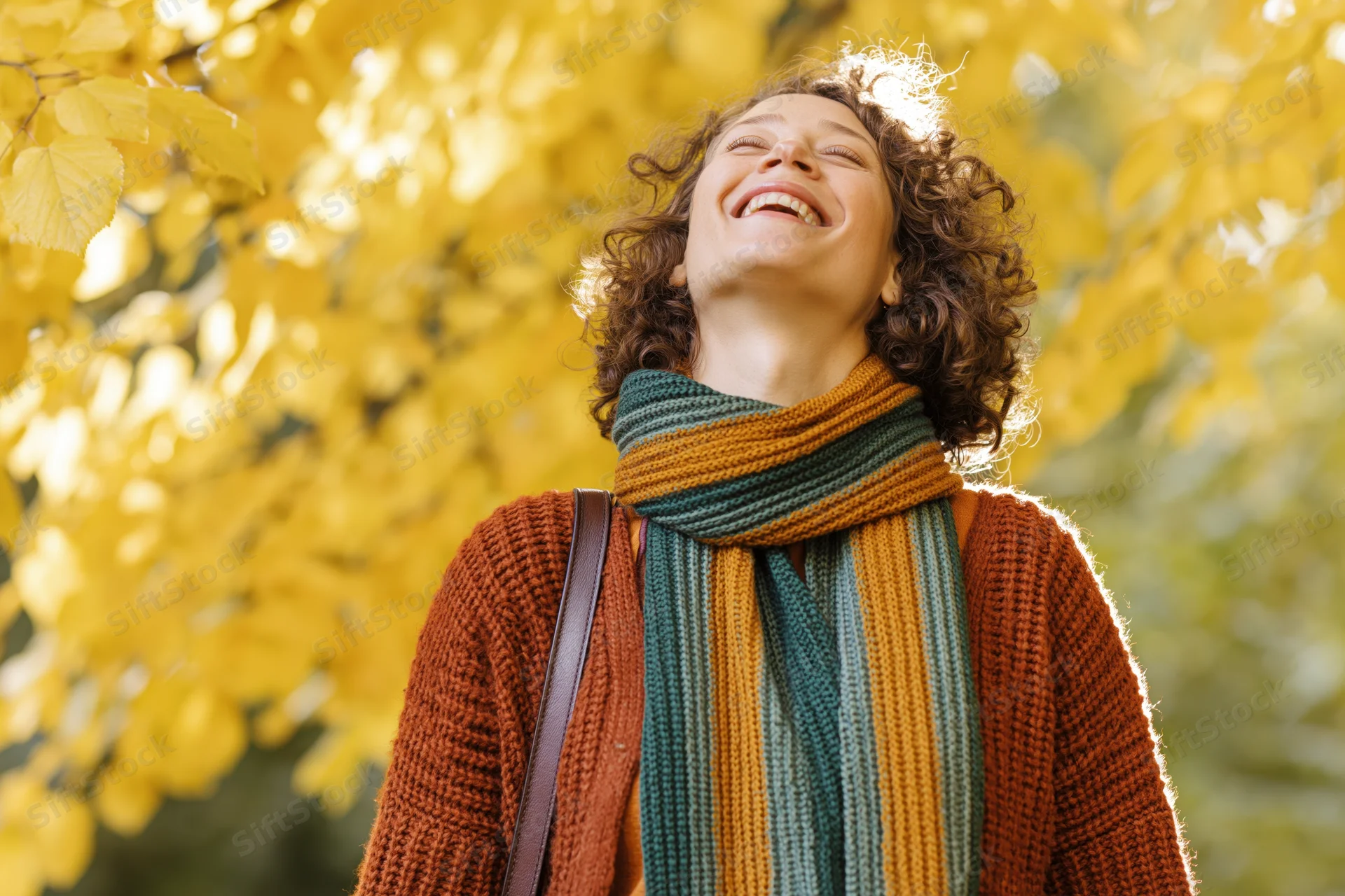 Woman laughing with head tilted up in autumn foliage