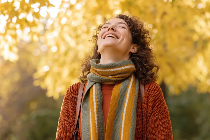 Woman laughing with head tilted back in autumn foliage