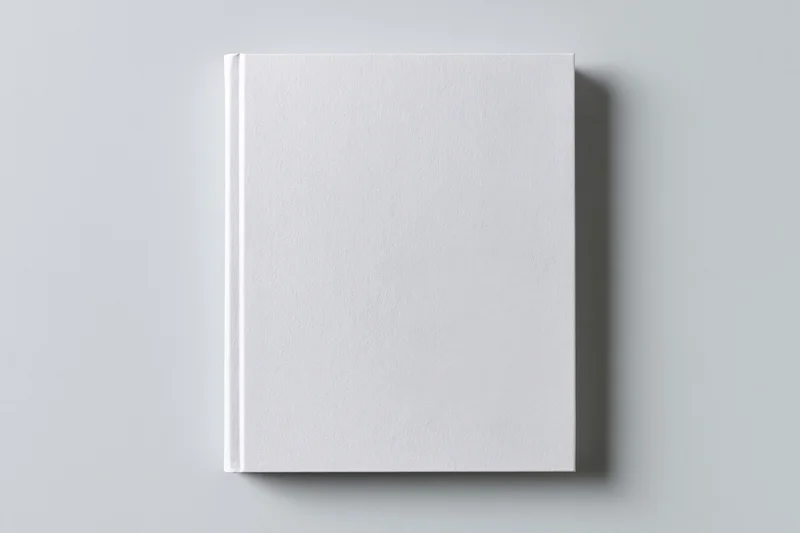 Blank white hardcover book standing upright on a gray surface