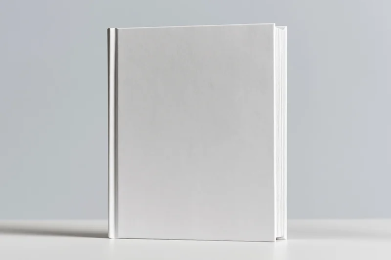 Blank white hardcover book standing upright on a white surface