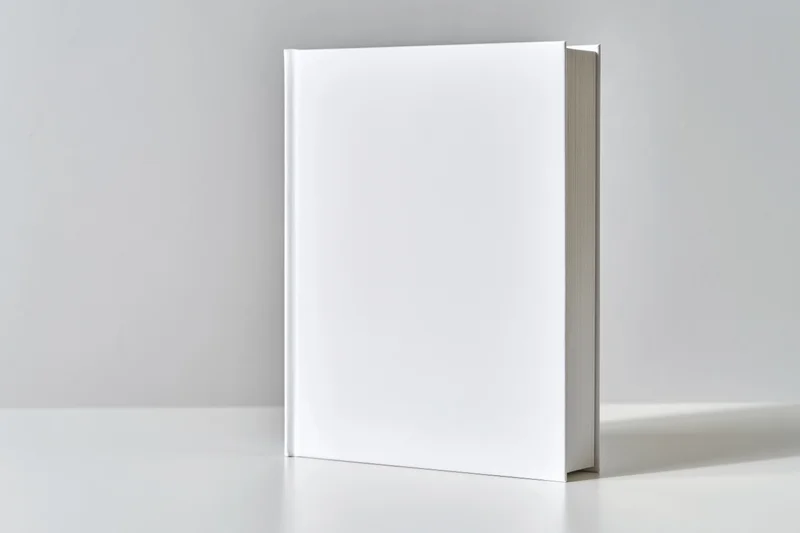 Blank white hardcover book standing upright on a white surface