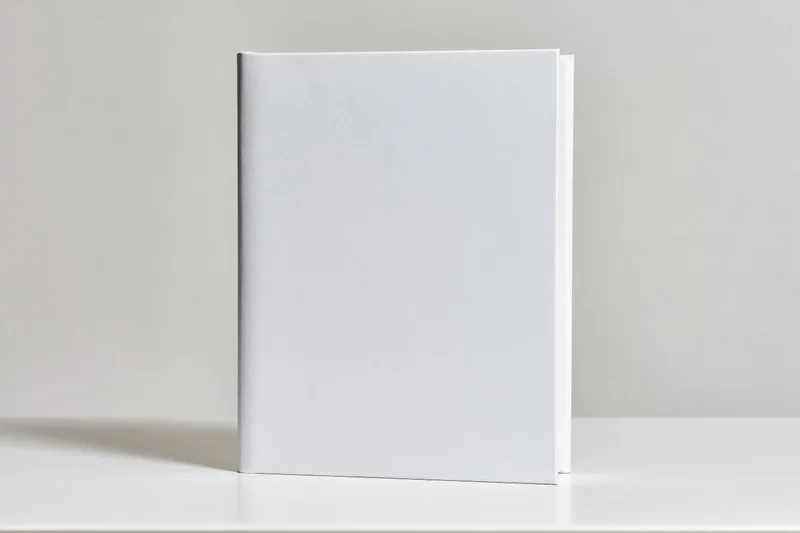 Blank white hardcover book standing upright on a white surface