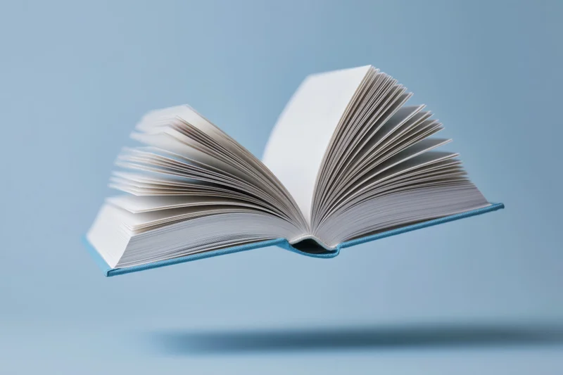 Open hardcover book floating midair with light blue cover against plain background