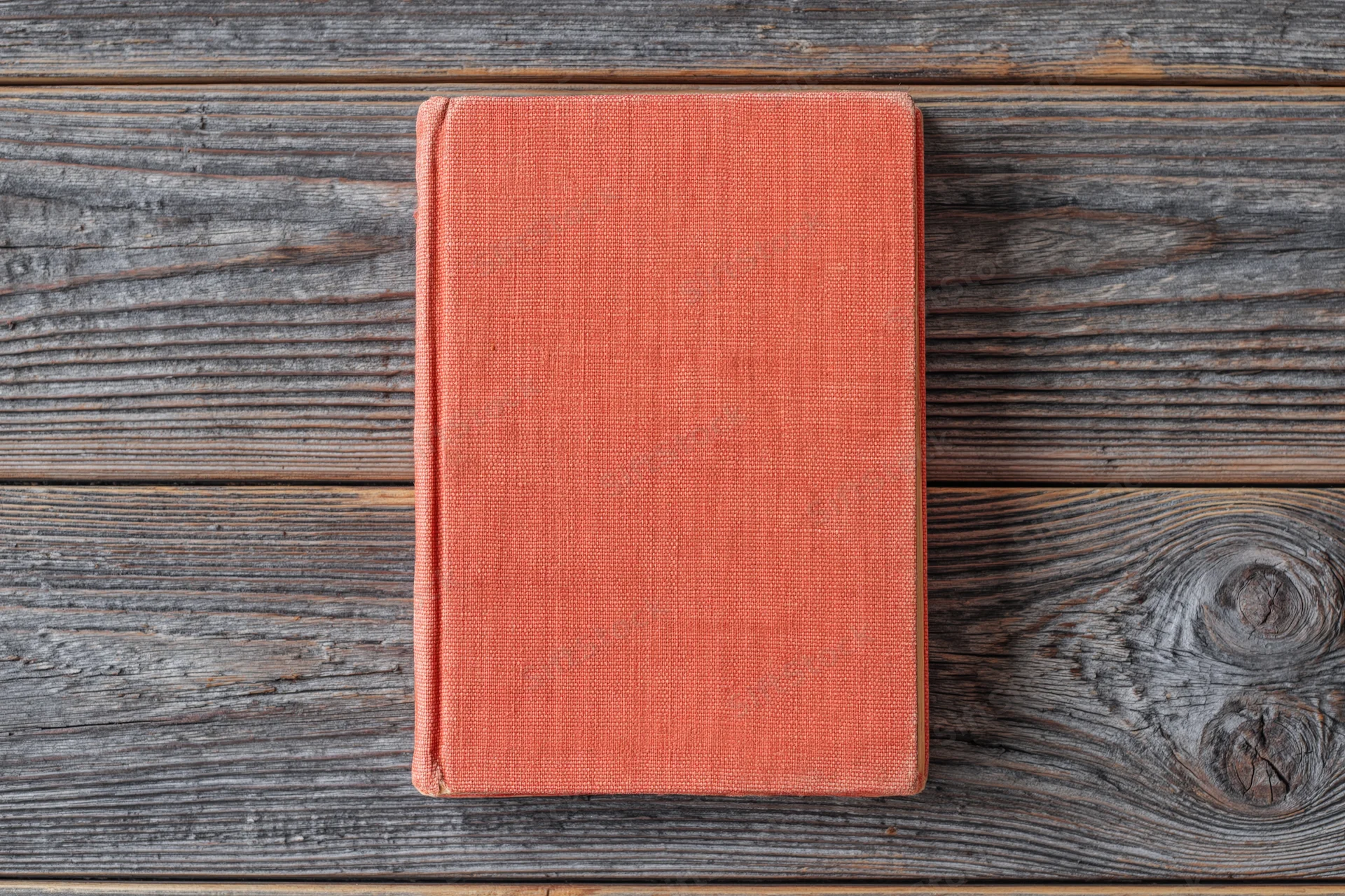 Red hardcover book lying flat on rustic wooden surface
