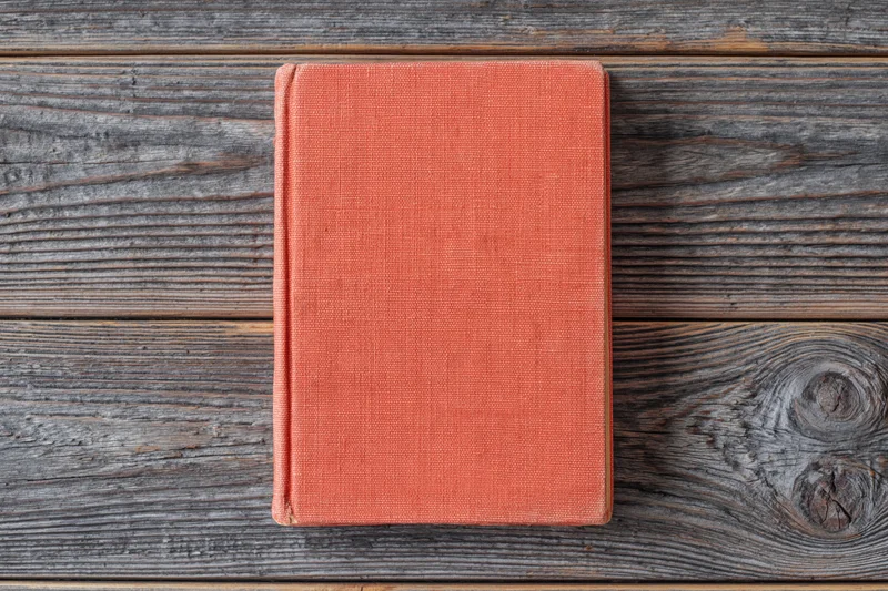 Red hardcover book lying flat on rustic wooden surface