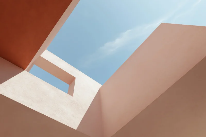 Upward view of abstract modern architectural structure with geometric forms and pastel walls against blue sky
